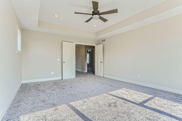 unfurnished bedroom with visible vents, baseboards, carpet, a tray ceiling, and recessed lighting