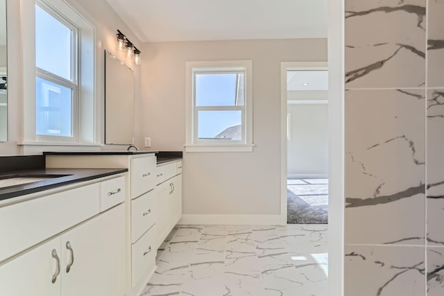 bathroom with marble finish floor, vanity, and baseboards