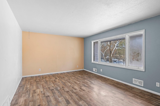 unfurnished room with baseboards, visible vents, and wood finished floors