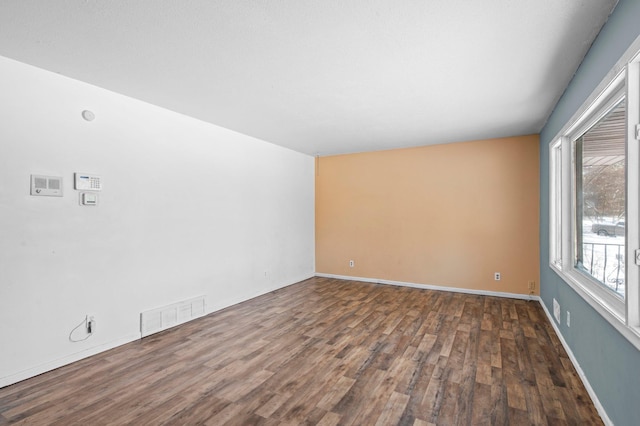 unfurnished room featuring visible vents, baseboards, and wood finished floors