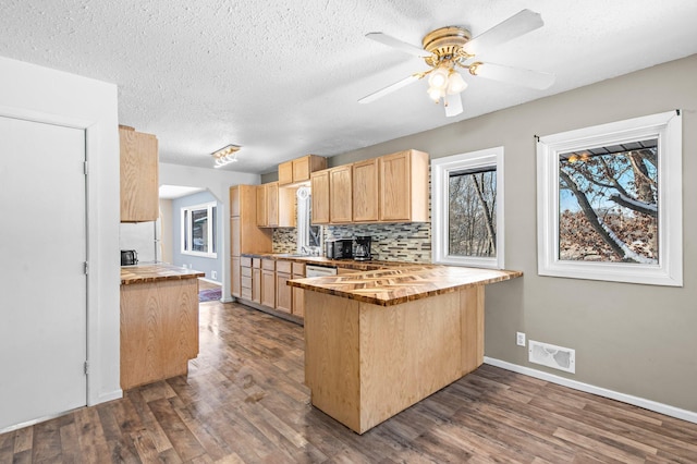 kitchen featuring dark wood-style floors, arched walkways, tasteful backsplash, visible vents, and a peninsula