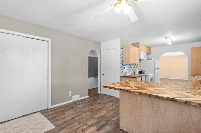 kitchen with dark wood-style floors, arched walkways, tasteful backsplash, wood counters, and white appliances