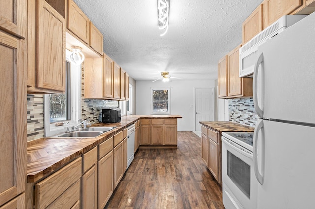 kitchen featuring dark wood finished floors, a ceiling fan, butcher block countertops, white appliances, and a peninsula