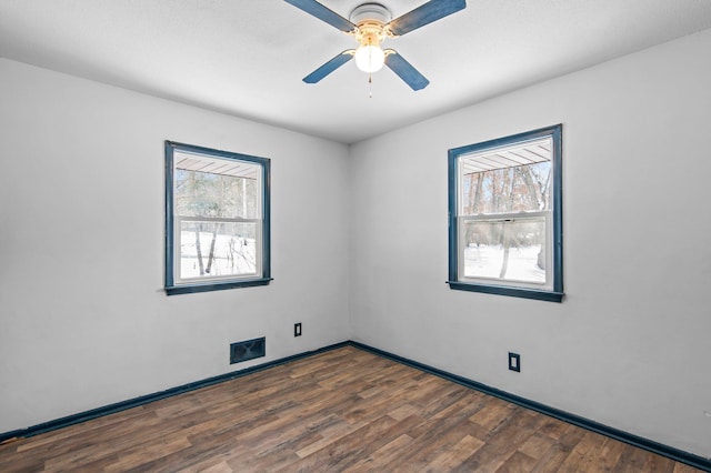 spare room with wood finished floors, a ceiling fan, and baseboards