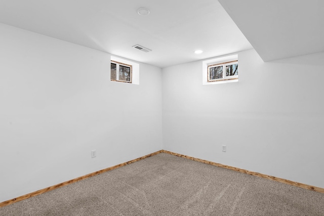 below grade area with carpet flooring, visible vents, and baseboards