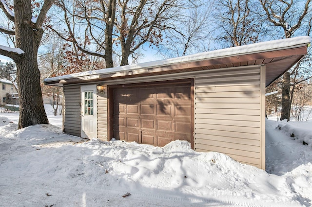 snow covered garage with a detached garage