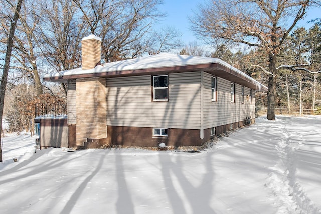 snow covered property with a chimney