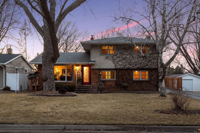 tri-level home featuring a detached garage, a front lawn, fence, a chimney, and an outdoor structure