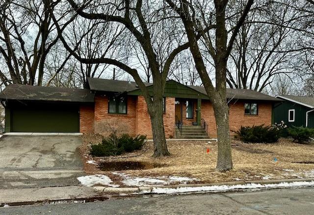 ranch-style house with driveway, an attached garage, and brick siding