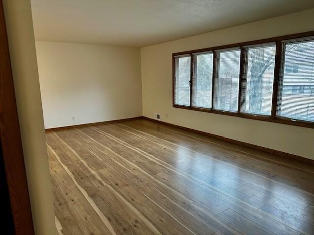 unfurnished room featuring a wealth of natural light, baseboards, and wood finished floors