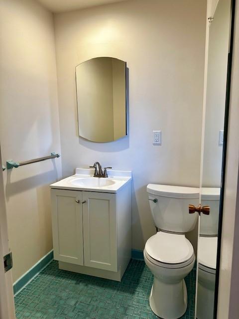 bathroom featuring toilet, baseboards, and vanity