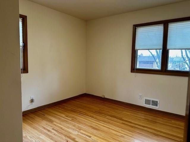 empty room with light wood-type flooring, baseboards, and visible vents