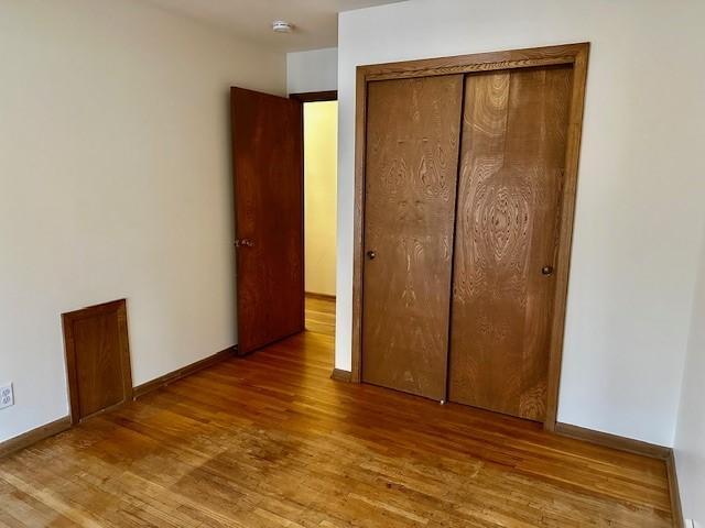 unfurnished bedroom featuring a closet, wood finished floors, and baseboards