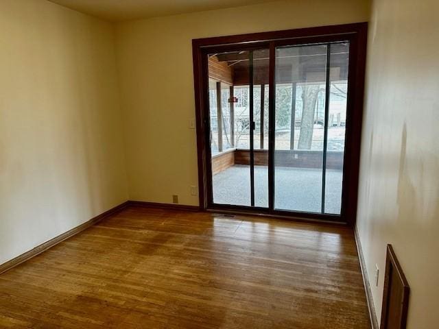 unfurnished room with baseboards and wood finished floors