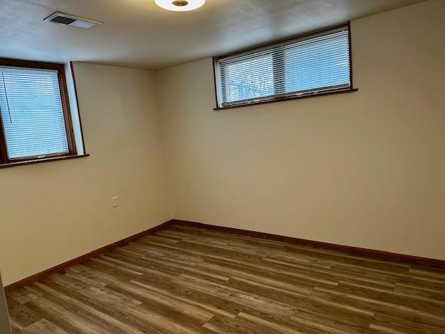 unfurnished room with dark wood-style floors, baseboards, and visible vents