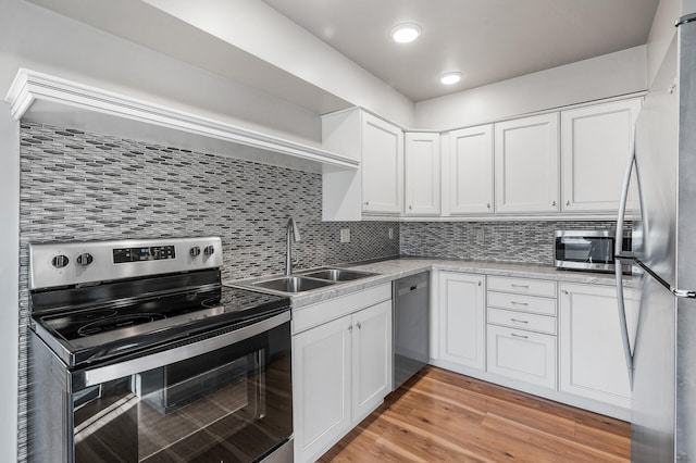 kitchen featuring white cabinetry, light wood-style flooring, appliances with stainless steel finishes, and a sink