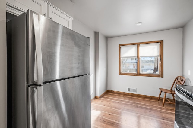 kitchen featuring visible vents, baseboards, freestanding refrigerator, white cabinets, and light wood-style floors