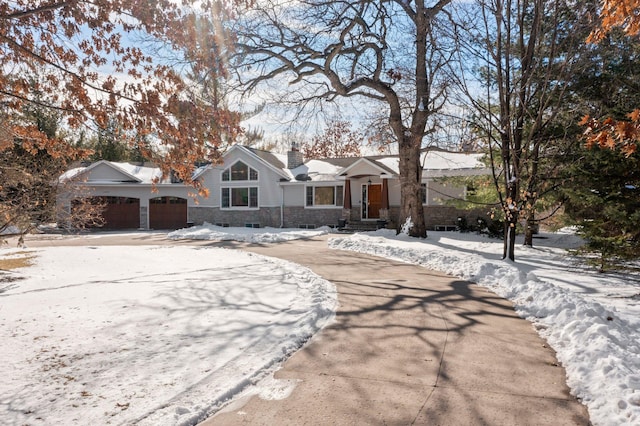 view of front facade featuring stone siding, an attached garage, a chimney, and driveway