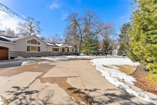 exterior space featuring an attached garage, stone siding, and driveway