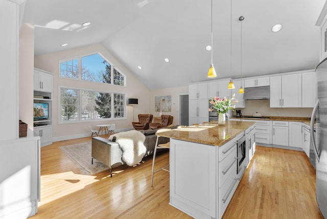 kitchen with under cabinet range hood, open floor plan, and white cabinetry