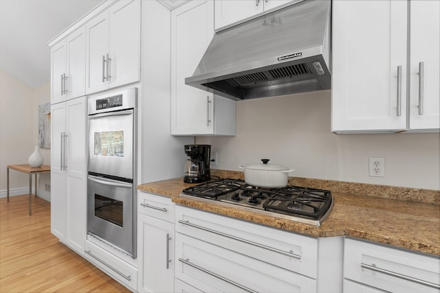 kitchen with ventilation hood, stainless steel appliances, and white cabinetry