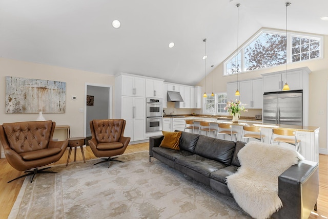 living room with light wood finished floors, recessed lighting, and high vaulted ceiling