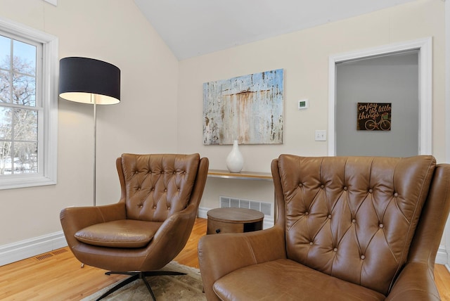 sitting room with visible vents, baseboards, lofted ceiling, and wood finished floors