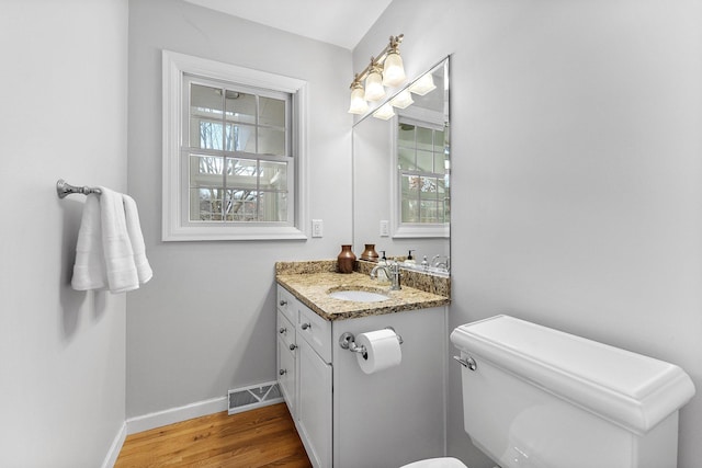 bathroom with a wealth of natural light, visible vents, baseboards, and wood finished floors