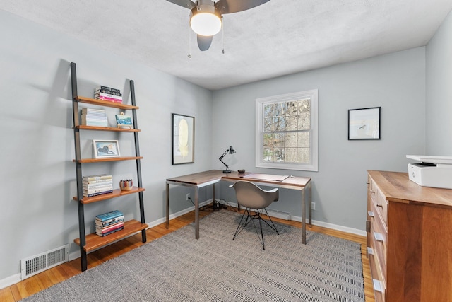 office area featuring visible vents, baseboards, wood finished floors, and a ceiling fan