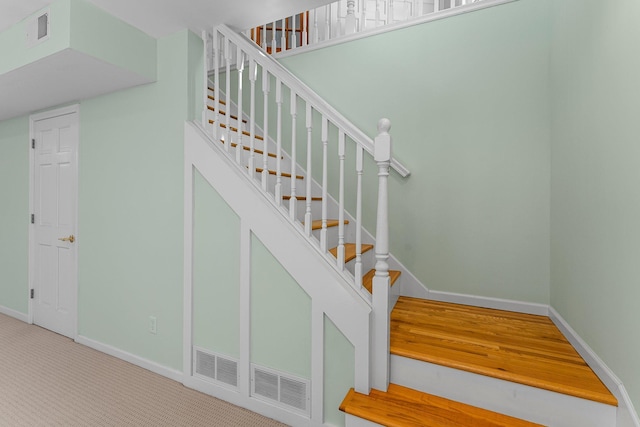 stairway featuring baseboards, visible vents, and carpet floors