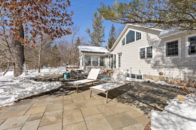 snow covered patio featuring a sunroom