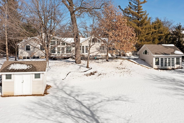 snowy yard with an outdoor structure, a storage unit, and a residential view