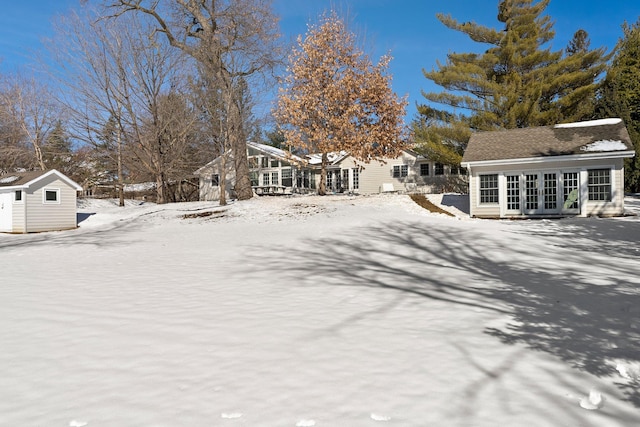 yard layered in snow with french doors and an outbuilding