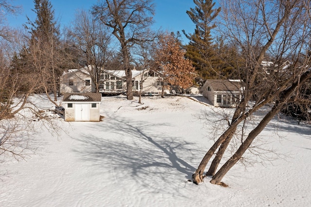 yard layered in snow featuring a storage unit and an outbuilding