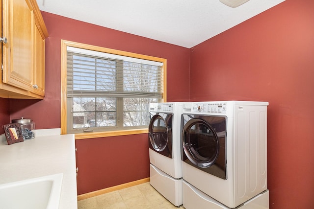 clothes washing area featuring baseboards, cabinet space, and washer and dryer