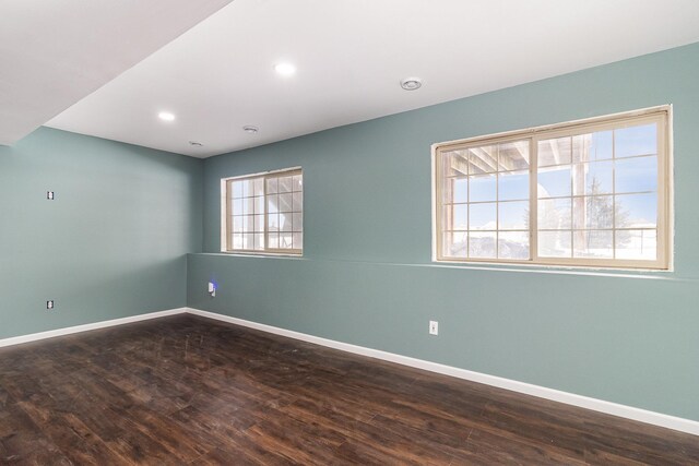 empty room with dark wood-style flooring, recessed lighting, and baseboards