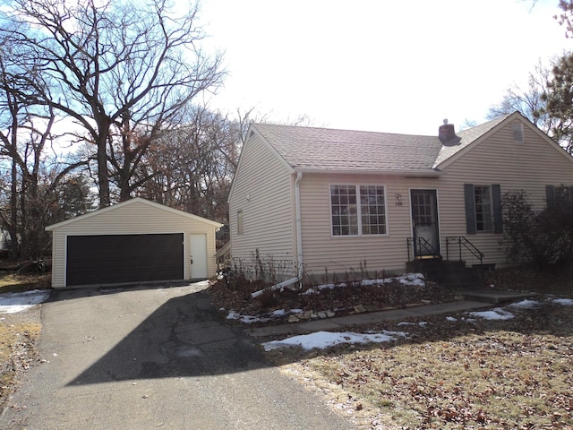 view of front of home featuring an outbuilding, a shingled roof, a chimney, and a detached garage