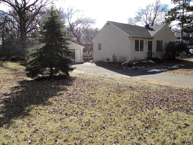 view of home's exterior with an outbuilding, roof with shingles, a chimney, and a garage