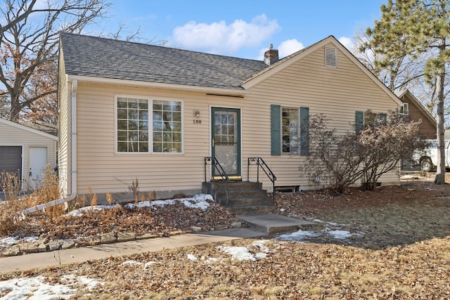 bungalow-style house with entry steps, a chimney, and roof with shingles