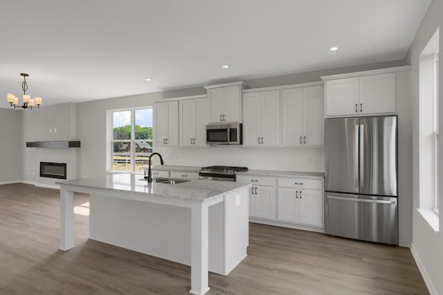 kitchen with a sink, stainless steel appliances, a glass covered fireplace, and white cabinetry