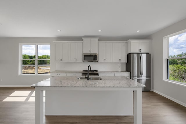 kitchen with a healthy amount of sunlight, a center island with sink, appliances with stainless steel finishes, and a sink