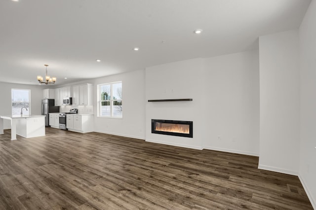 unfurnished living room with visible vents, baseboards, dark wood finished floors, recessed lighting, and a glass covered fireplace