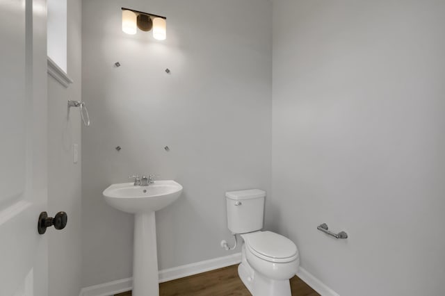 bathroom with baseboards, toilet, and wood finished floors