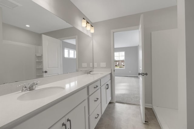 bathroom with double vanity, baseboards, and a sink