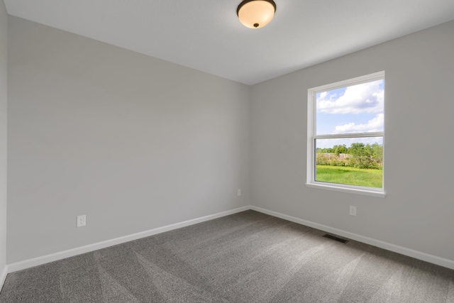 empty room featuring carpet flooring, visible vents, and baseboards