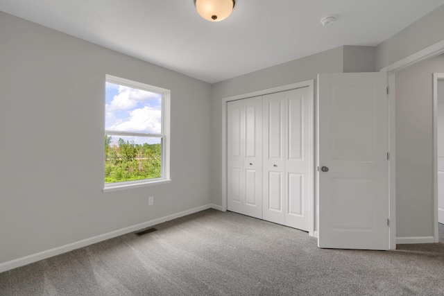 unfurnished bedroom featuring carpet flooring, baseboards, visible vents, and a closet