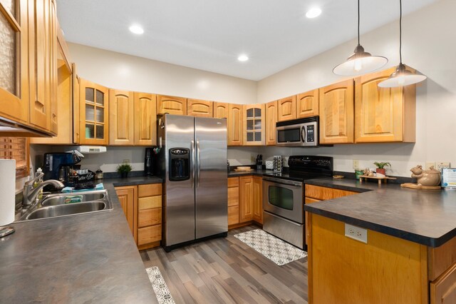 kitchen featuring appliances with stainless steel finishes, dark countertops, a sink, and glass insert cabinets