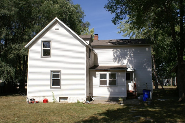 rear view of property with a chimney and a yard