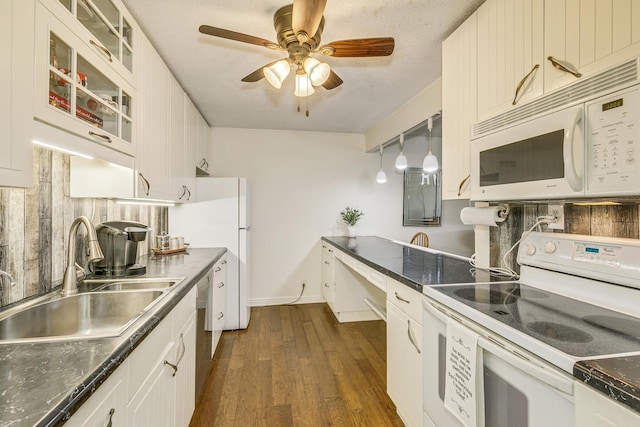 kitchen featuring glass insert cabinets, dark countertops, white appliances, and a sink