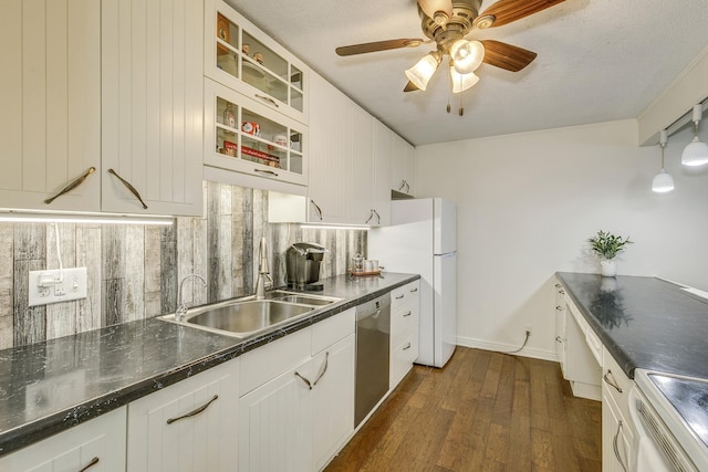 kitchen featuring a sink, white cabinets, tasteful backsplash, dark countertops, and glass insert cabinets